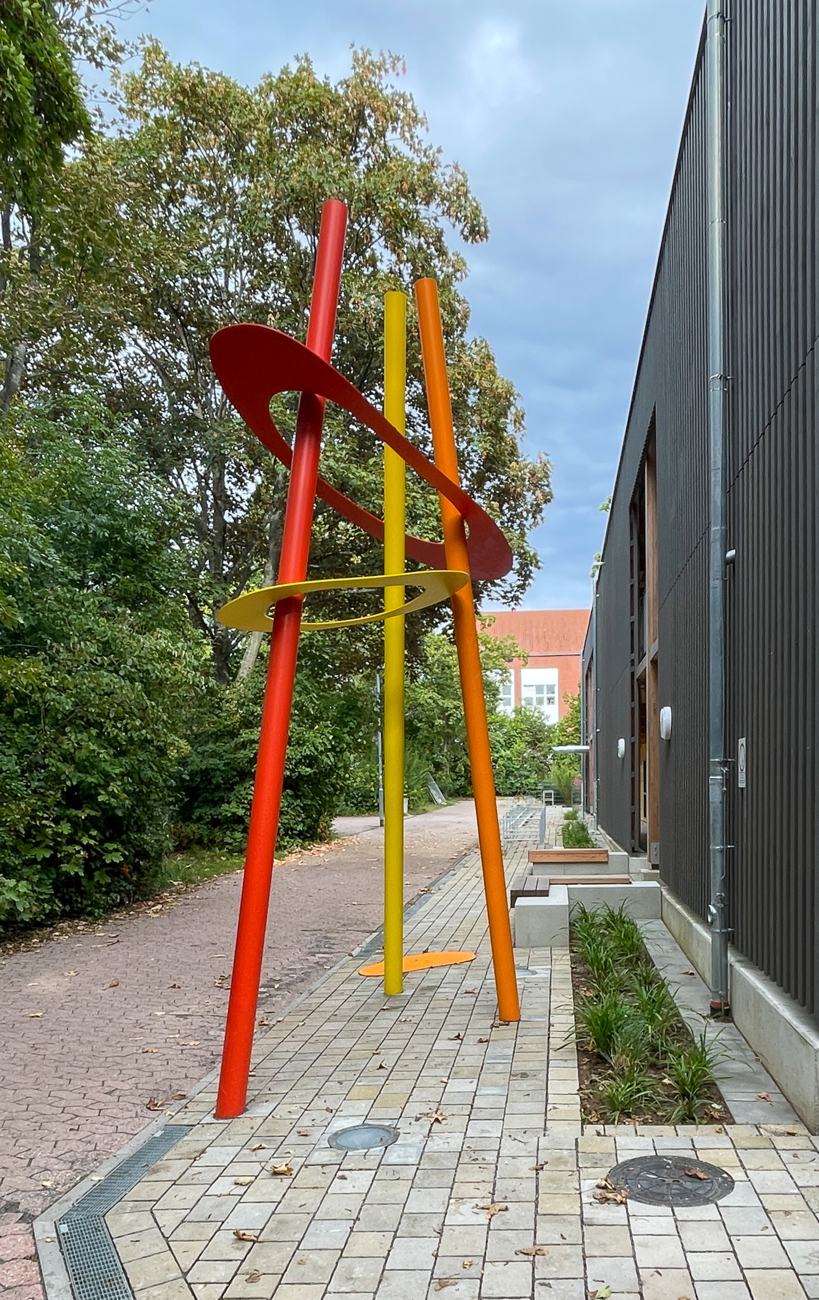Rundrohre und amorphe Formen greifen die Vertikale der Lamellenfassade räumlich auf.