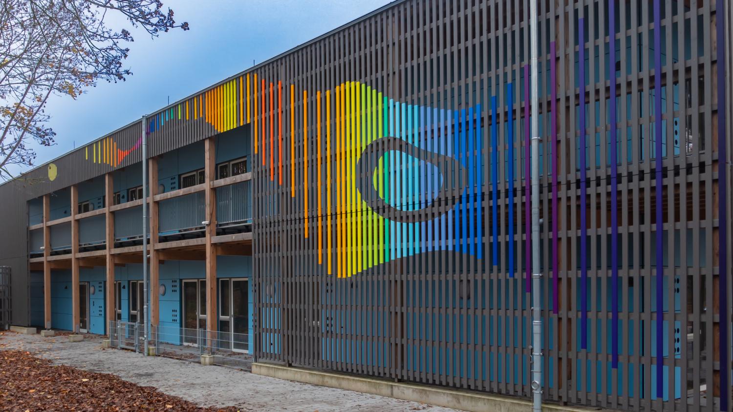 Die farbig gefasste Fassade öffnet sich als Farbenmeer zum Himmel.